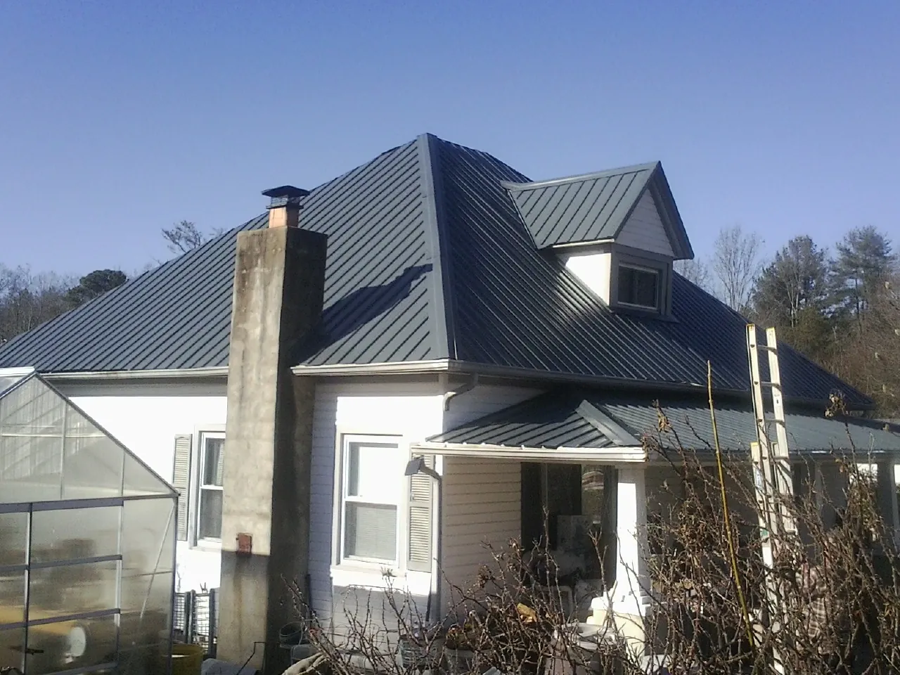 Dark blue standing seam metal roof on a white farmhouse with dormer — Slate & Tile Roof Repair by Roofing Brothers in Vonore