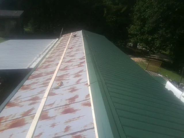 Old rusted panels beside newly installed green metal roofing — Wind Damage Roof Repair by Roofing Brothers in Vonore